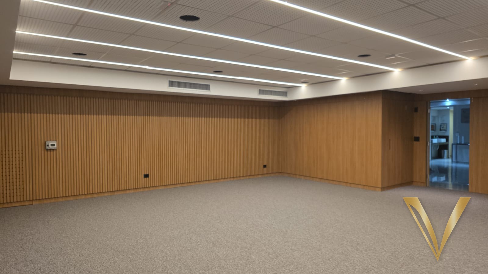 Sala corporativa revestida em lambri de carvalho liso e ripado com iluminação linear