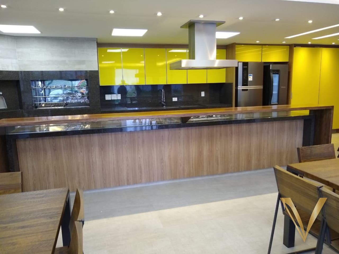 Espaço gourmet com armários em laca amarela alto brilho, churrasqueira e balcão em madeira