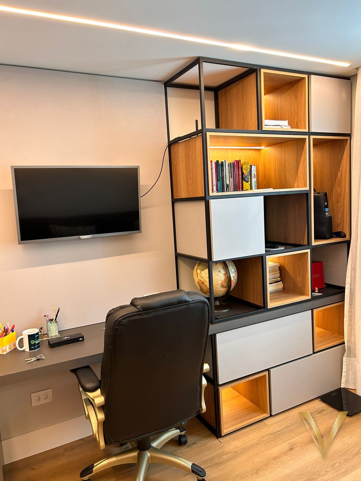 Home office com estante em estrutura metálica preta, nichos em madeira e bancada integrada