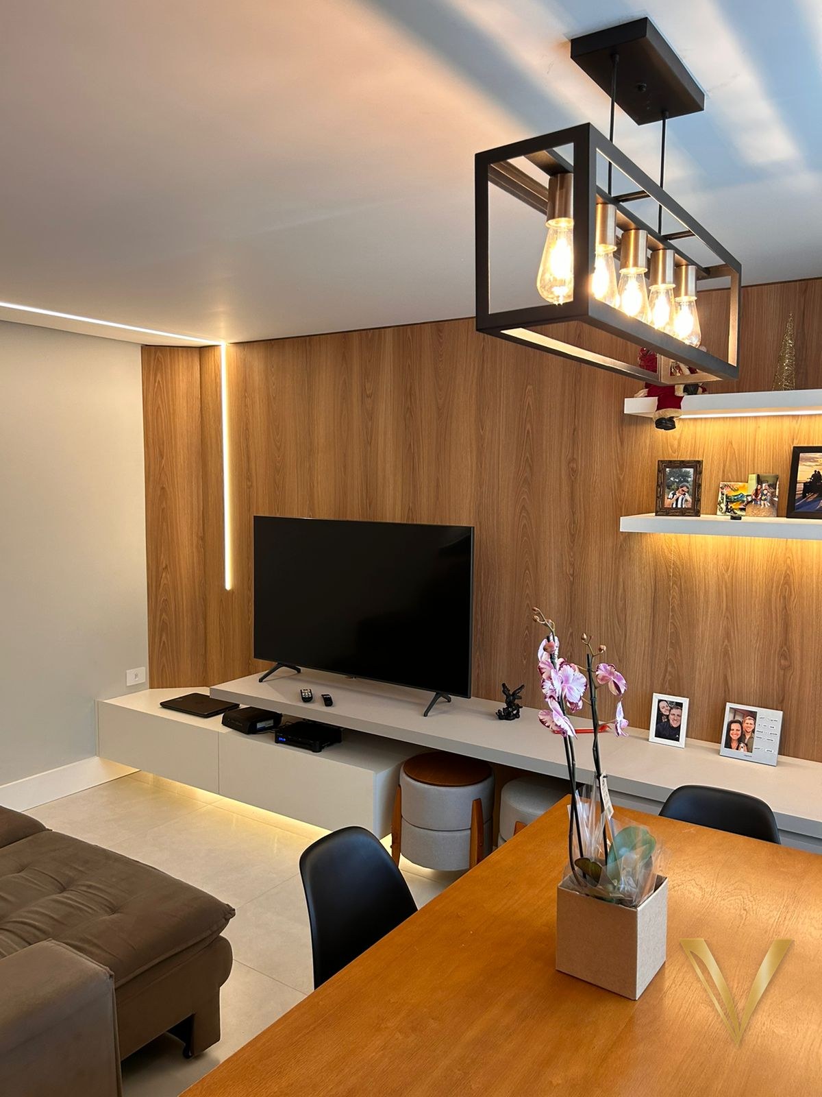 Living com painel de madeira do piso ao teto, rack branco suspenso e prateleiras iluminadas