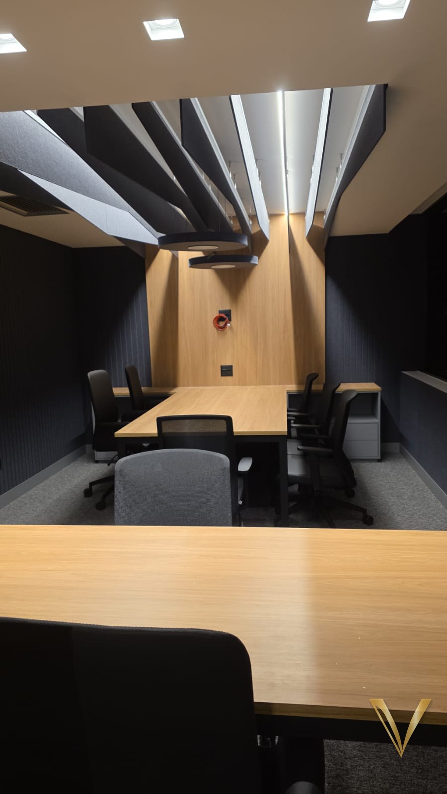 Sala de reunião com mesa em carvalho, painel de fundo em madeira e forro acústico