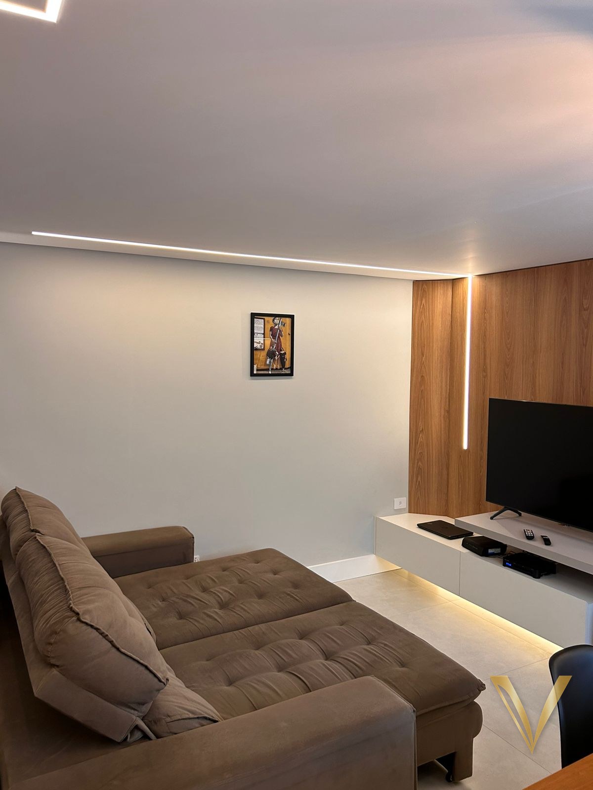 Sala de estar com sanca iluminada e painel de madeira ao fundo