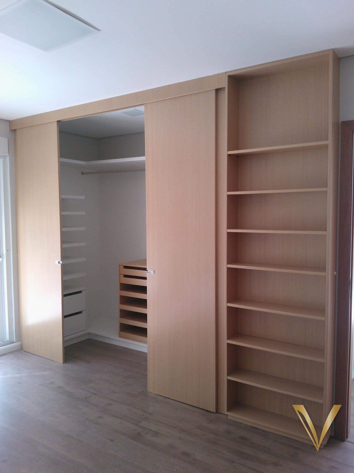 Mesmo armário com a porta de correr aberta, revelando o closet com gaveteiro e sapateira