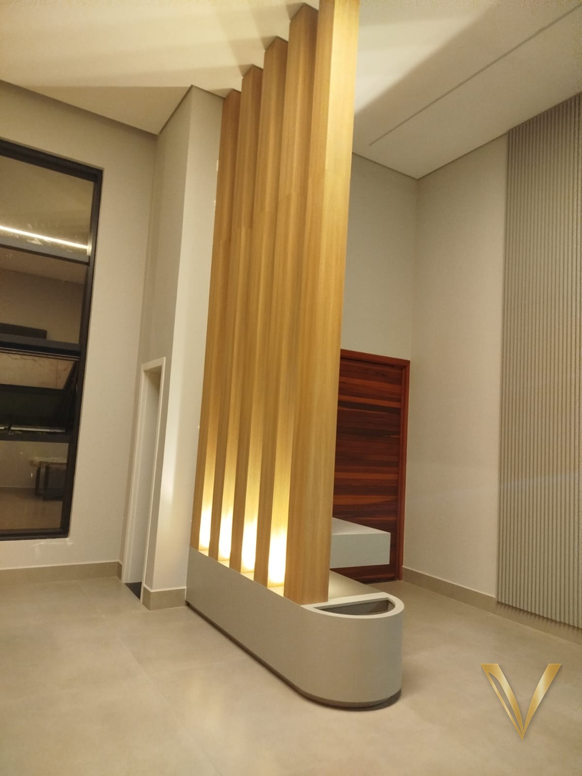 Hall de entrada com brise vertical de madeira em pé-direito duplo e jardineira curva