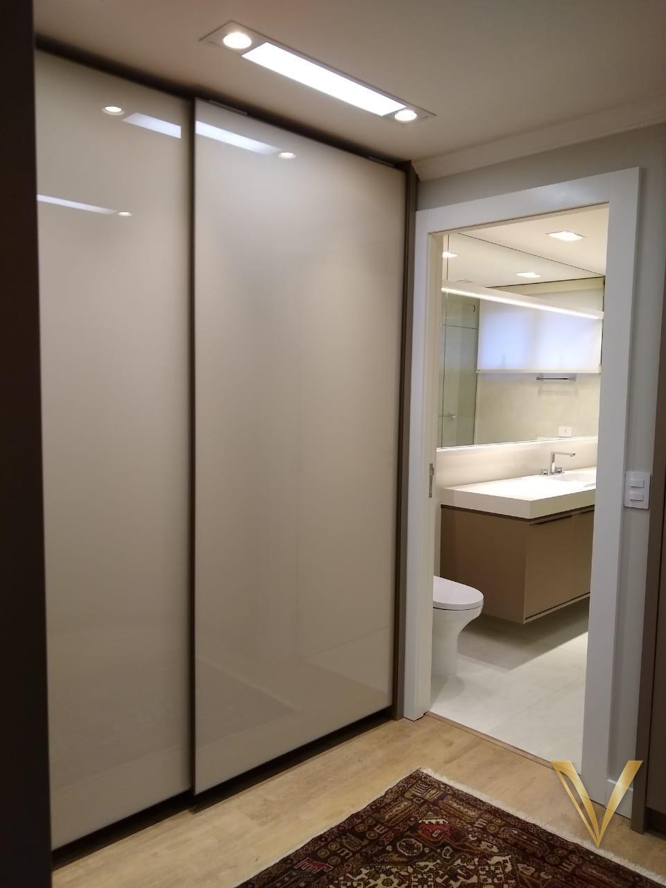 Closet com portas de correr em vidro laqueado e acesso ao lavabo com bancada suspensa