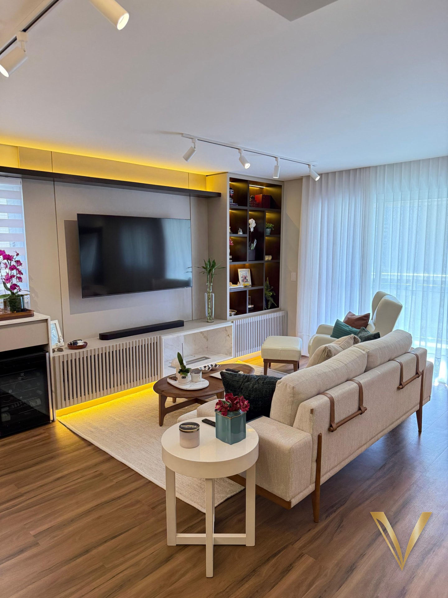 Living integrado com painel de TV, estante de nichos iluminados e luz indireta